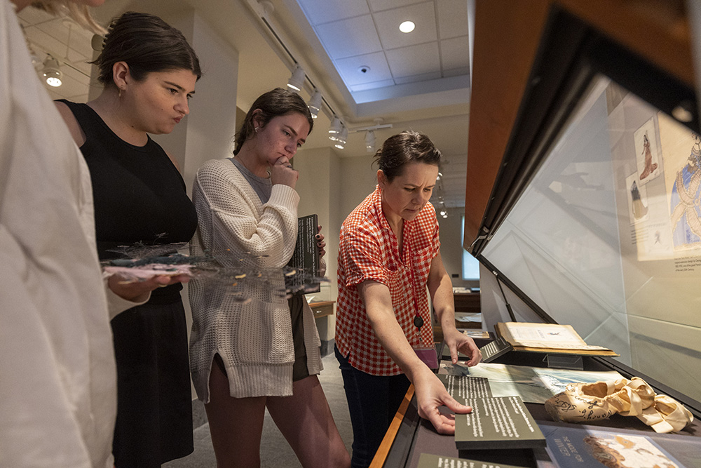 Archivist Jan Hebbard shows a group of students some items in an exhibit case