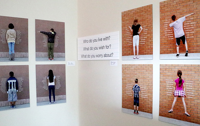 Photos of 8 children facing a brick wall, with their words on the wall around them. 