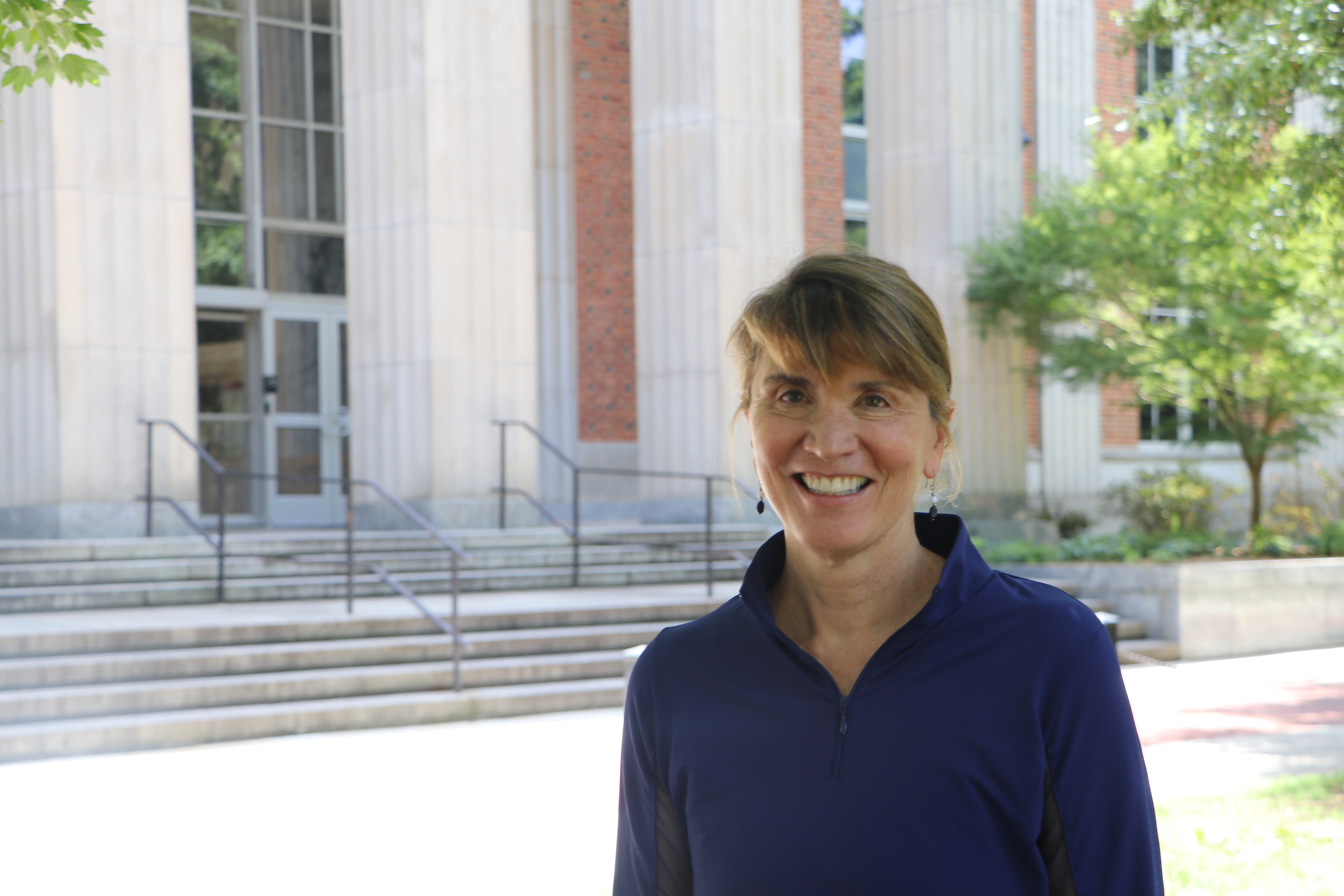 Woman in blue shirt smiles in front of Main Library