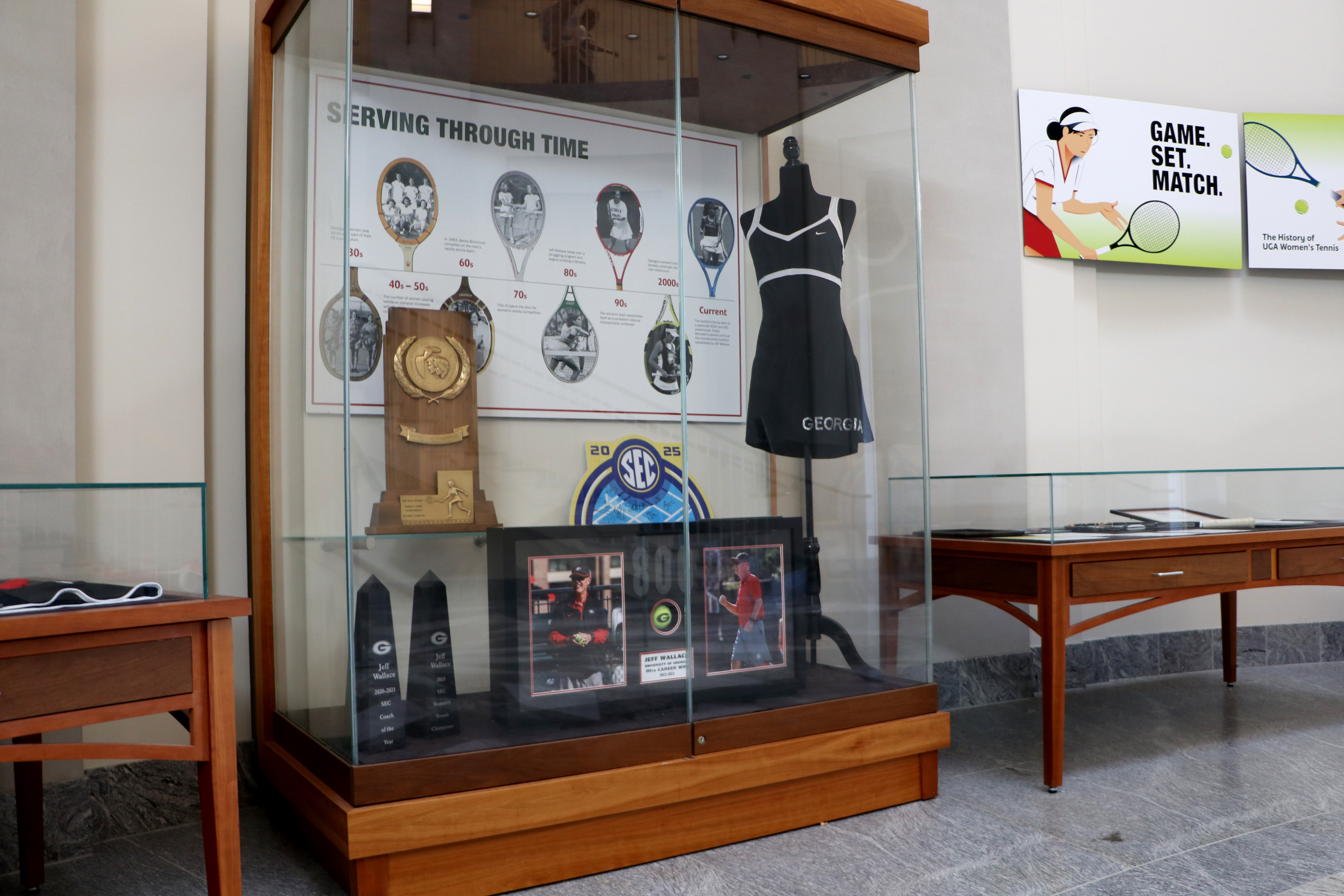 Display case with history of UGA women's tennis, including trophy and uniform
