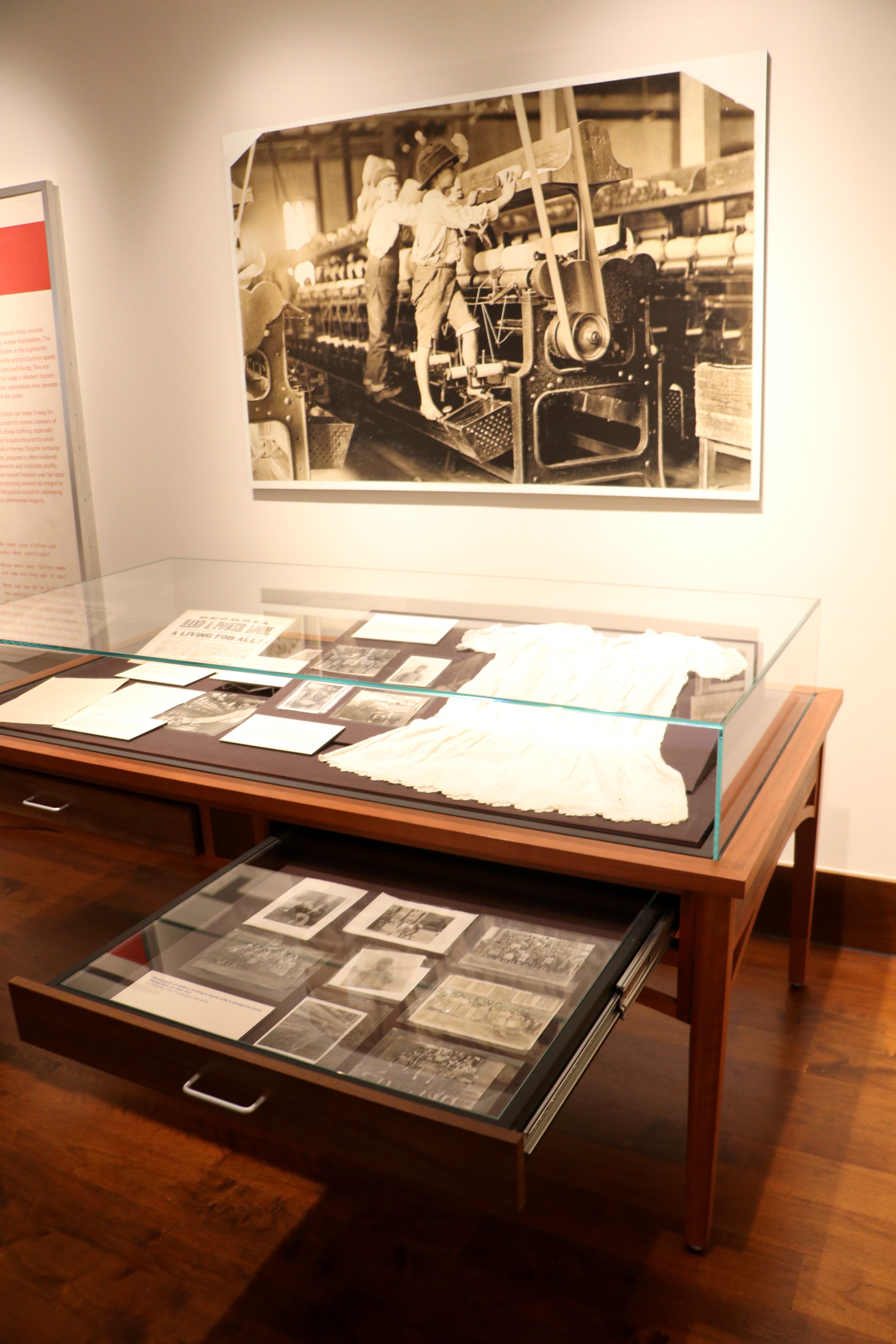 Display case with cotton shirt and photographs of textile laborers