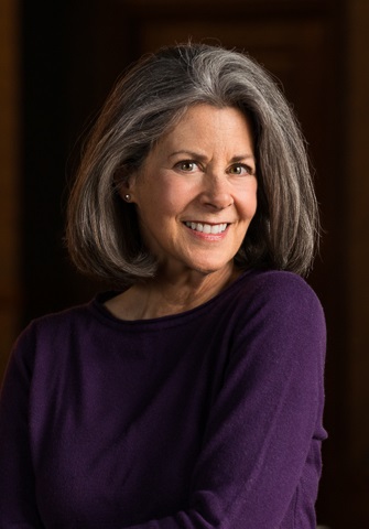 Photo of a middle-aged woman with her hair in a bob, wearing a purple shirt, smiling for the camera