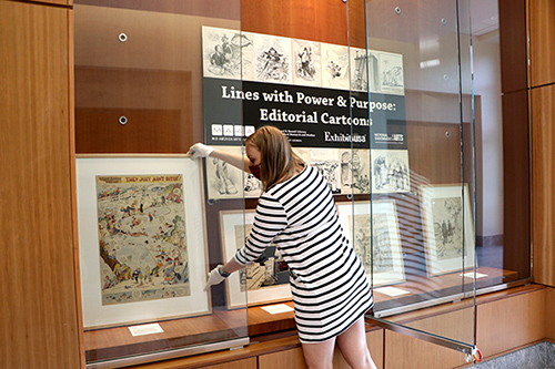 Archivist installs early 20th century editorial cartoons for the exhibit