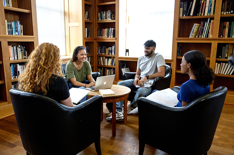 A group of students meets around a table in the MLC reading room