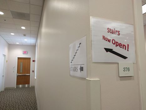 Hallway leading to stairwell marked by sign saying "Stairs Now Open!"