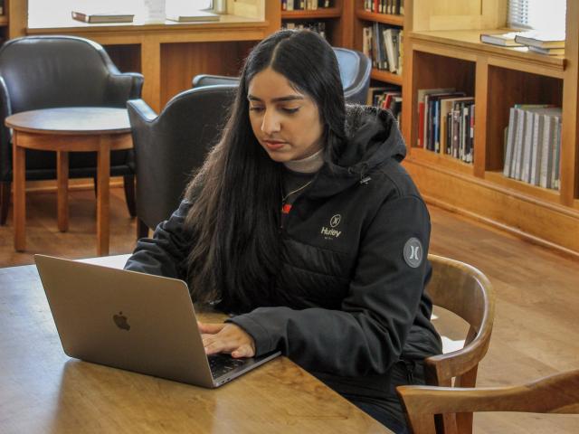 Student working on laptop at table in  Reading Room