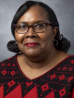 Woman with glasses. She's wearing a red and black sweater.