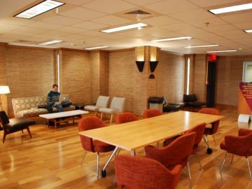 A warm space with tables and soft seating. Furniture is in a midcentury modern style. 